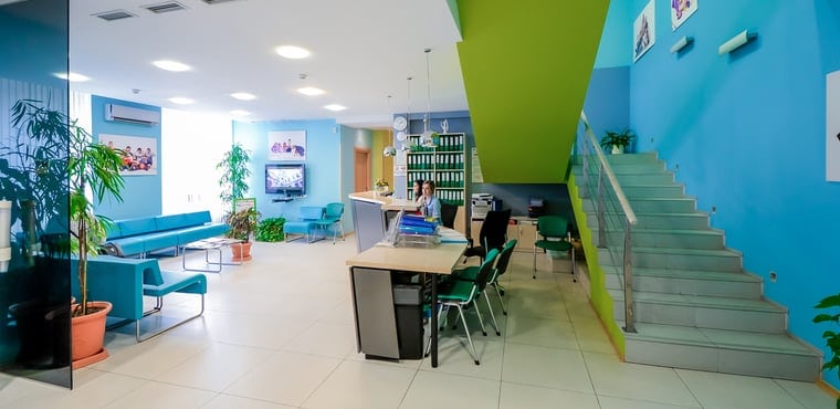 Recepción moderna de oficina con escaleras y plantas.