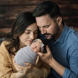 Familia con bebé recién nacido abrazando.